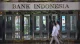 Pedestrians walk past the Bank Indonesia headquarters building