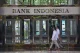 Pedestrians walk past the Bank Indonesia headquarters building