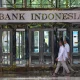 Pedestrians walk past the Bank Indonesia headquarters building