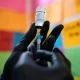 Gloved hand holding a Moderna vaccine vial and syringe