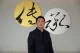 Raffles Family Office CEO Chi-Man Kwan standing in front of decorative calligraphy art